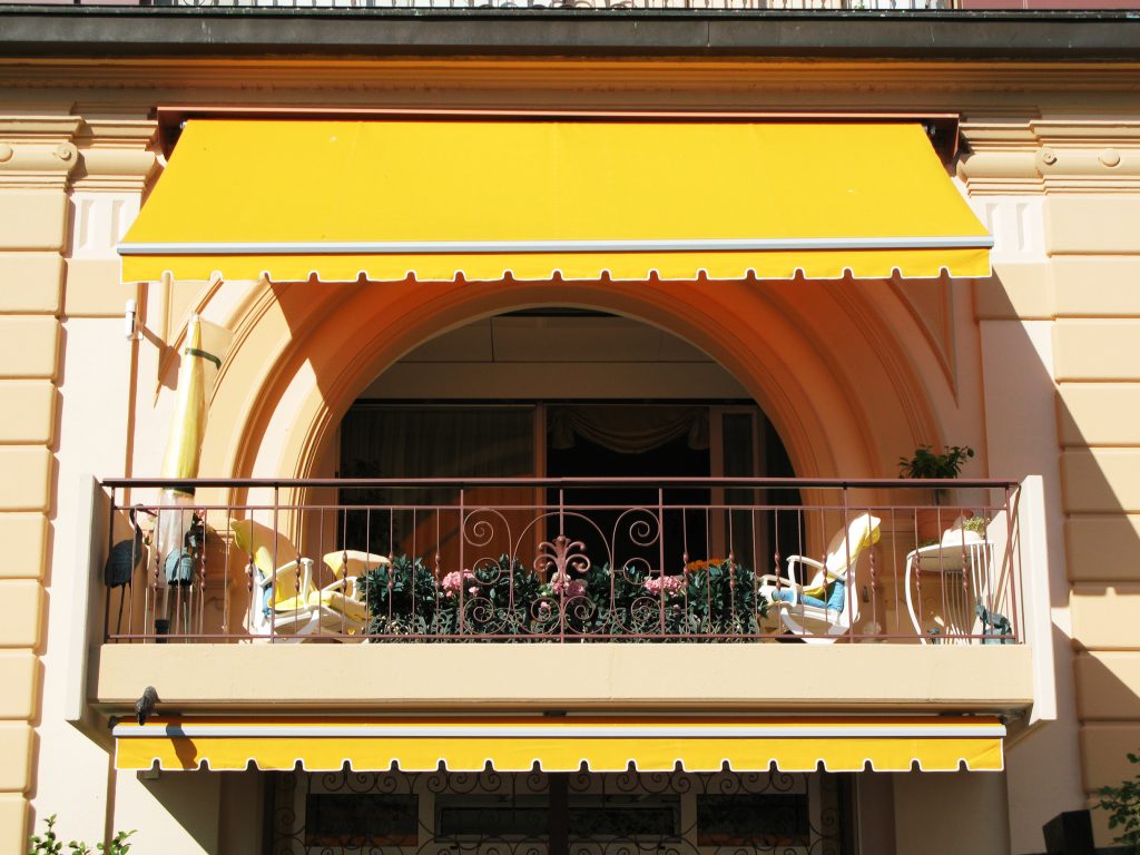 Hotel with yellow awning on apartment balcony